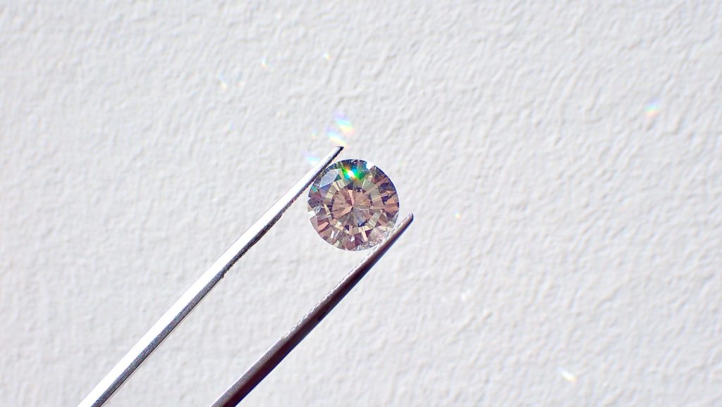 A diamond being held between tweezers